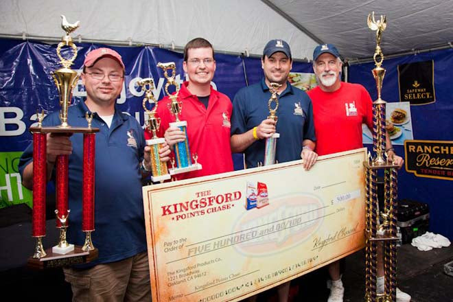 Pork Barrel BBQ team holding trophy and check after winning BBQ competition